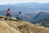 Two mountain bikers on a trail with a scenic mountain landscape in the background